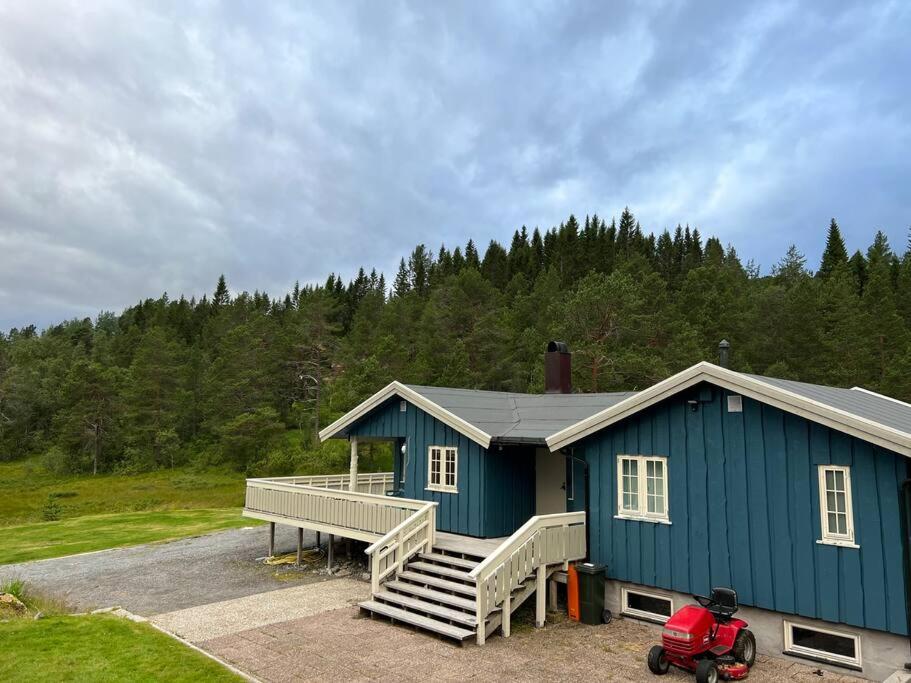 uma casa azul com uma moto estacionada em frente em Frittliggende hytte i flott turterreng em Molde