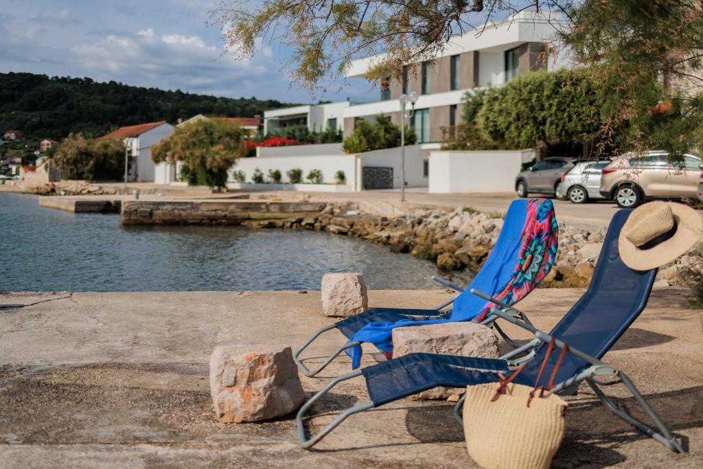 普萊克的住宿－Traditional holiday house by the sea，两把椅子和一顶帽子坐在水边