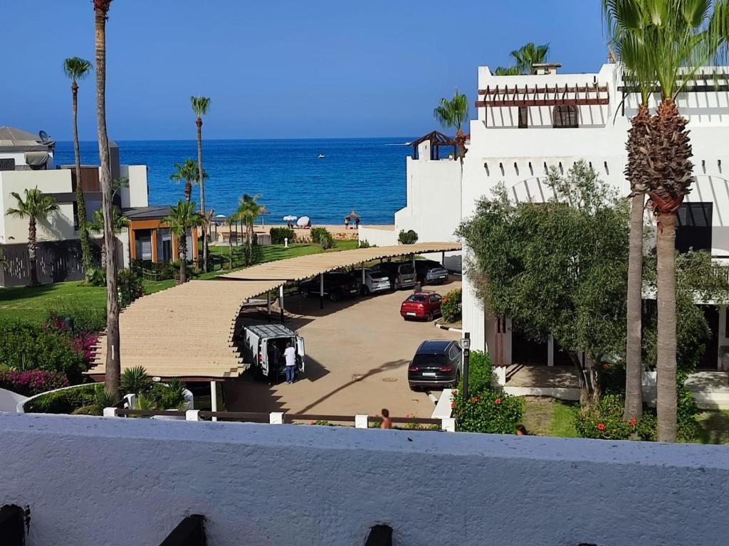 a view of a building with a parking lot and the ocean at Beach House in KSAR RIMAL in Marina Smir