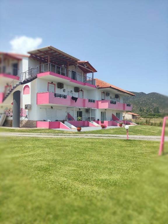 a pink and white building with a grass field at Vigla House in Sykia Chalkidikis