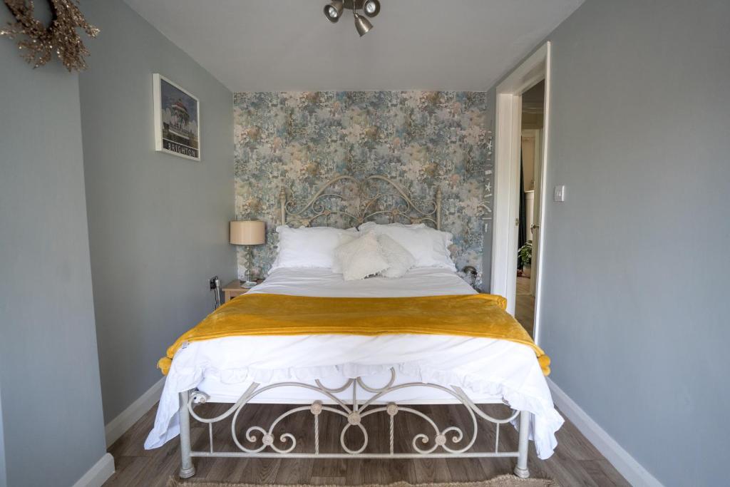 1 dormitorio con 1 cama y papel pintado con motivos florales en Driftwood by the Sea, en Brighton & Hove