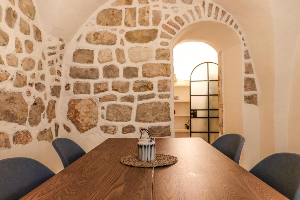 a dining room with a table and a stone wall at Cozy Heritage Home Jerusalem in Jerusalem