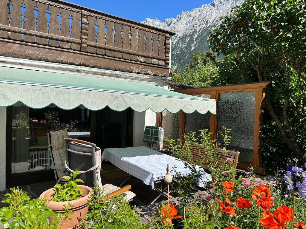 un patio con mesa, sillas y flores en Ferienhaus Abendfrieden, en Mittenwald