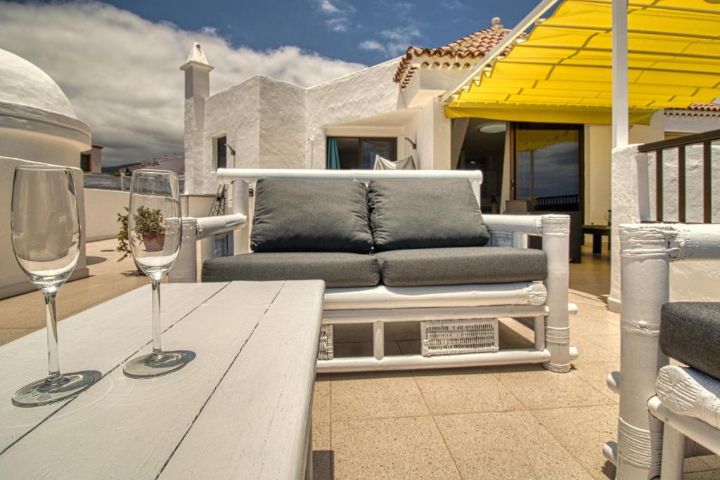 een tafel met twee wijnglazen op een patio bij Luxury Penthouse Sea View Jacuzzy & pool wiffi free in Playa Fañabe