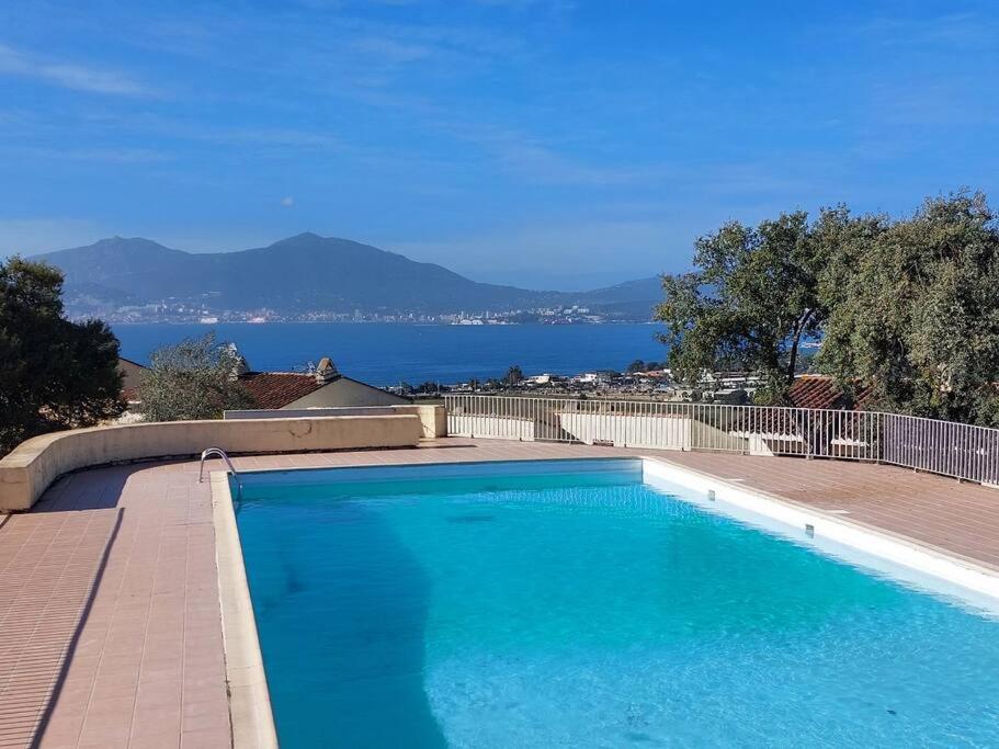 une grande piscine bleue avec vue sur l'eau dans l'établissement T3 climatisé vue mer piscine tennis, à Grosseto-Prugna