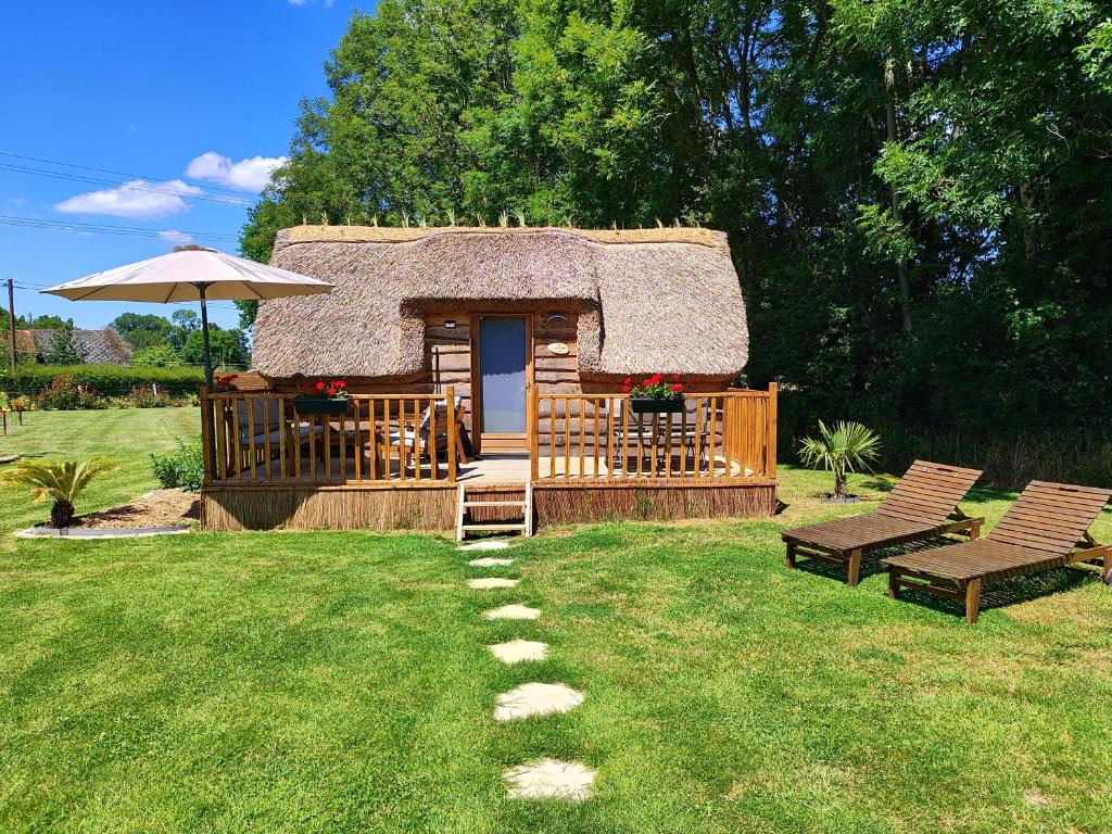 Cette cabane en rondins dispose d'un toit de chaume et d'une terrasse. dans l'établissement Les Mini-Chaumières, à Saint-Martin-Saint-Firmin