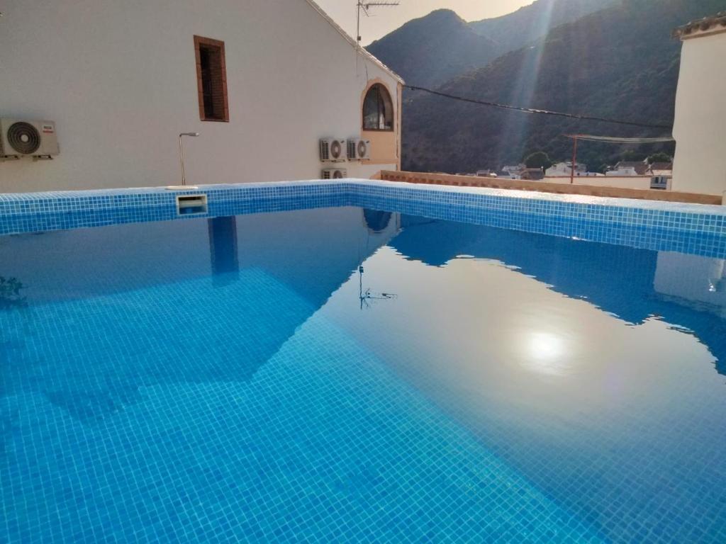 a swimming pool with blue water in front of a building at Casa El Cerro in Cortes de la Frontera