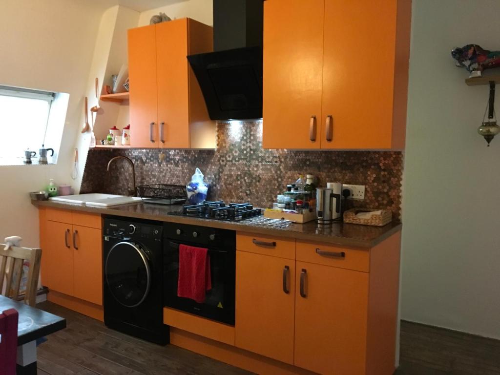 uma cozinha com armários laranja e um forno com placa de fogão em The Crescent em Barking