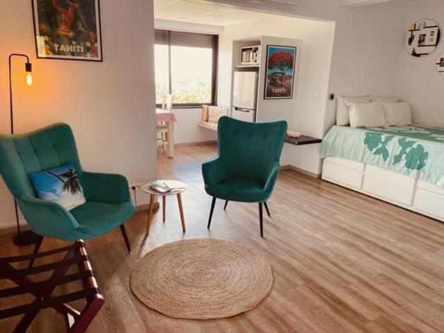 a living room with two chairs and a bed at Studio Teiki - calme, proche centre-ville, ferry & aéroport in Papeete