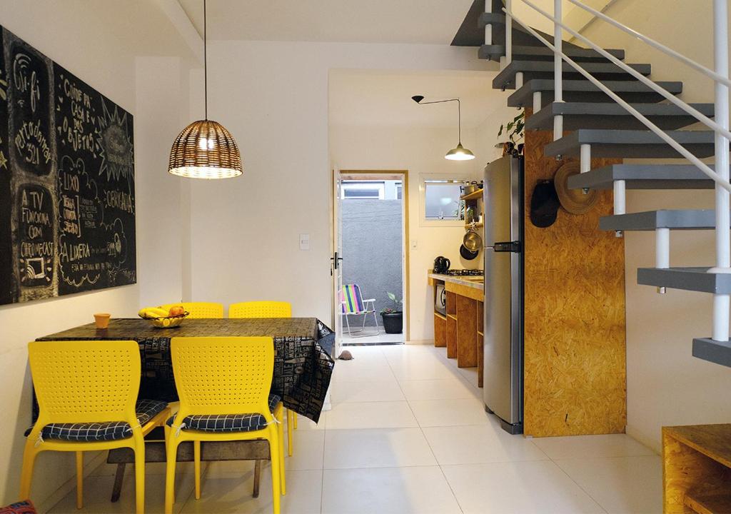 uma cozinha e sala de jantar com mesa e cadeiras amarelas em Casa na Praia do Campeche em Florianópolis