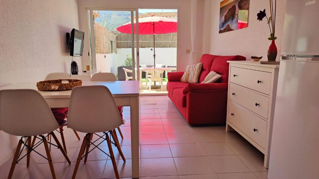 uma cozinha e sala de estar com uma mesa e um sofá vermelho em Port de la Selva apartament em Port de la Selva