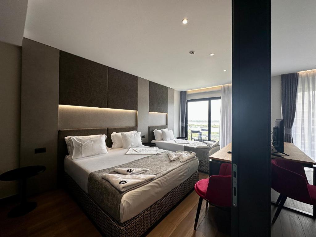 a hotel room with a bed and a desk at Frojd Kune Resort & Beach Hotel in Shëngjin