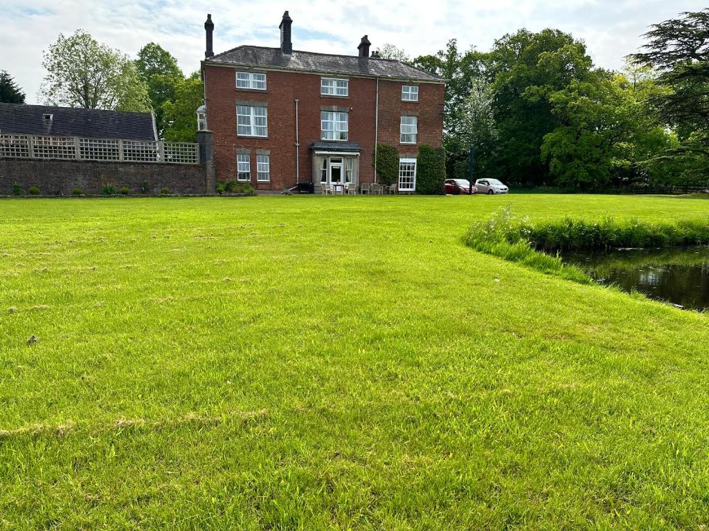 un grand champ herbeux devant un grand bâtiment en briques dans l'établissement Coundon Lodge Coventry, à Coventry