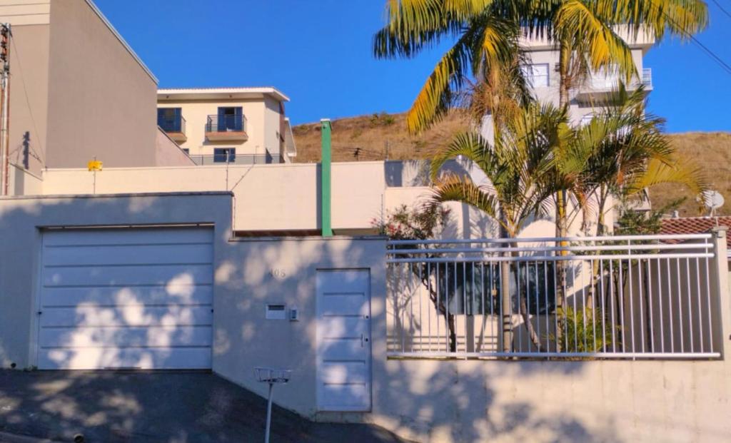 a house with a garage and a palm tree at Casa espaçosa em Poços de Caldas in Poços de Caldas