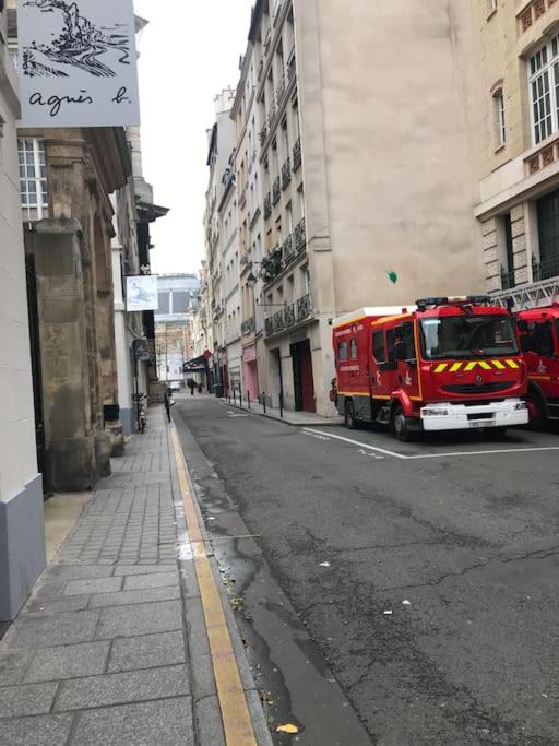 a red fire truck driving down a city street at Appartement design à la bourse du commerce in Paris