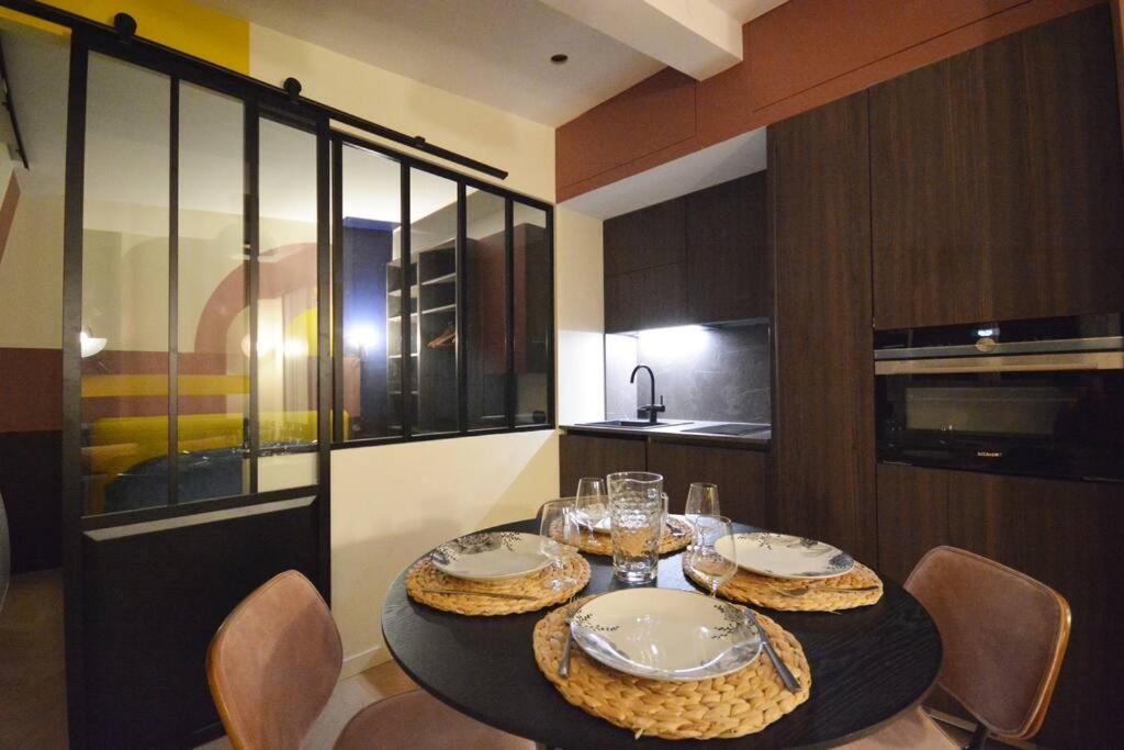 a kitchen with a table with plates and glasses on it at Appartement design à la bourse du commerce in Paris