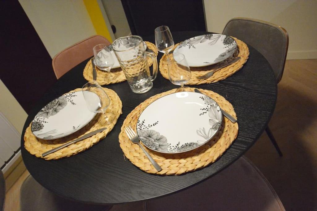 a table with four plates and glasses on it at Appartement design à la bourse du commerce in Paris
