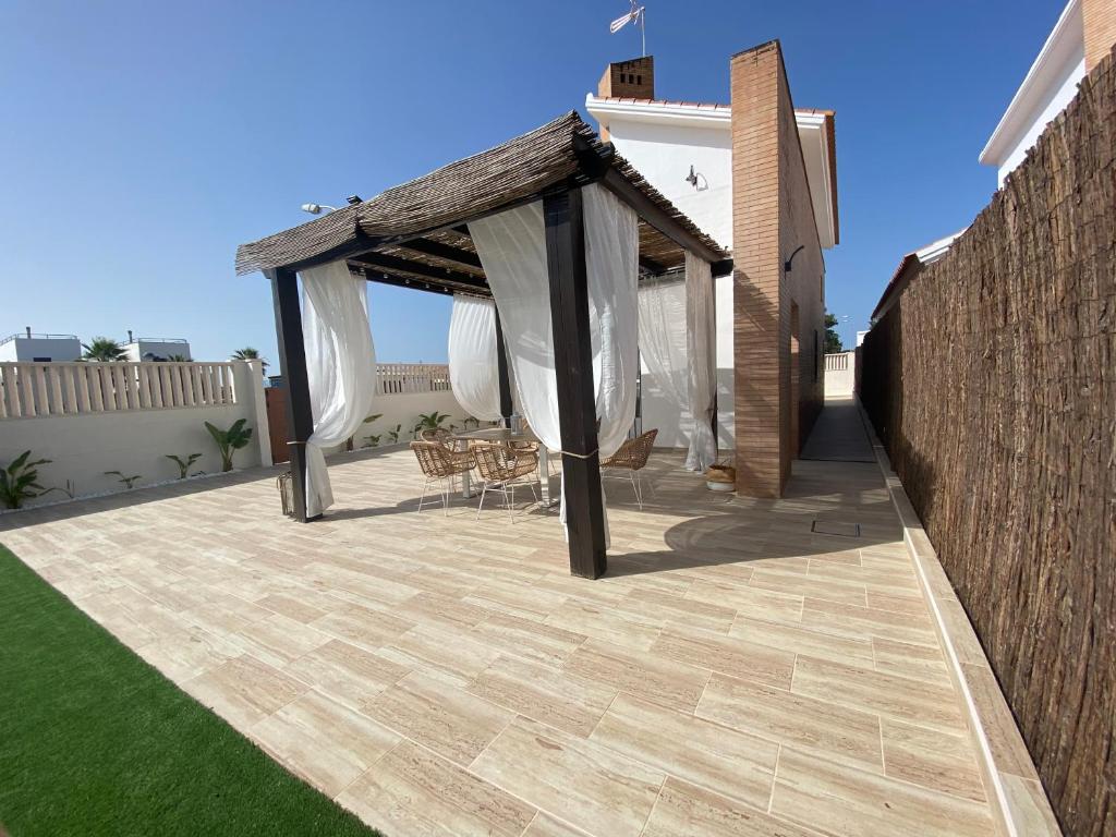 - un pavillon avec une table et des chaises sur la terrasse dans l'établissement Villa Fumarel, à Matalascañas