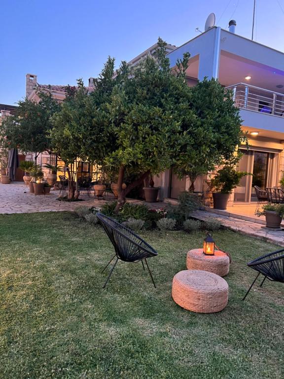 a building with two chairs and a candle in the grass at Carpe Diem Corinthian Suites Ι in Krínai