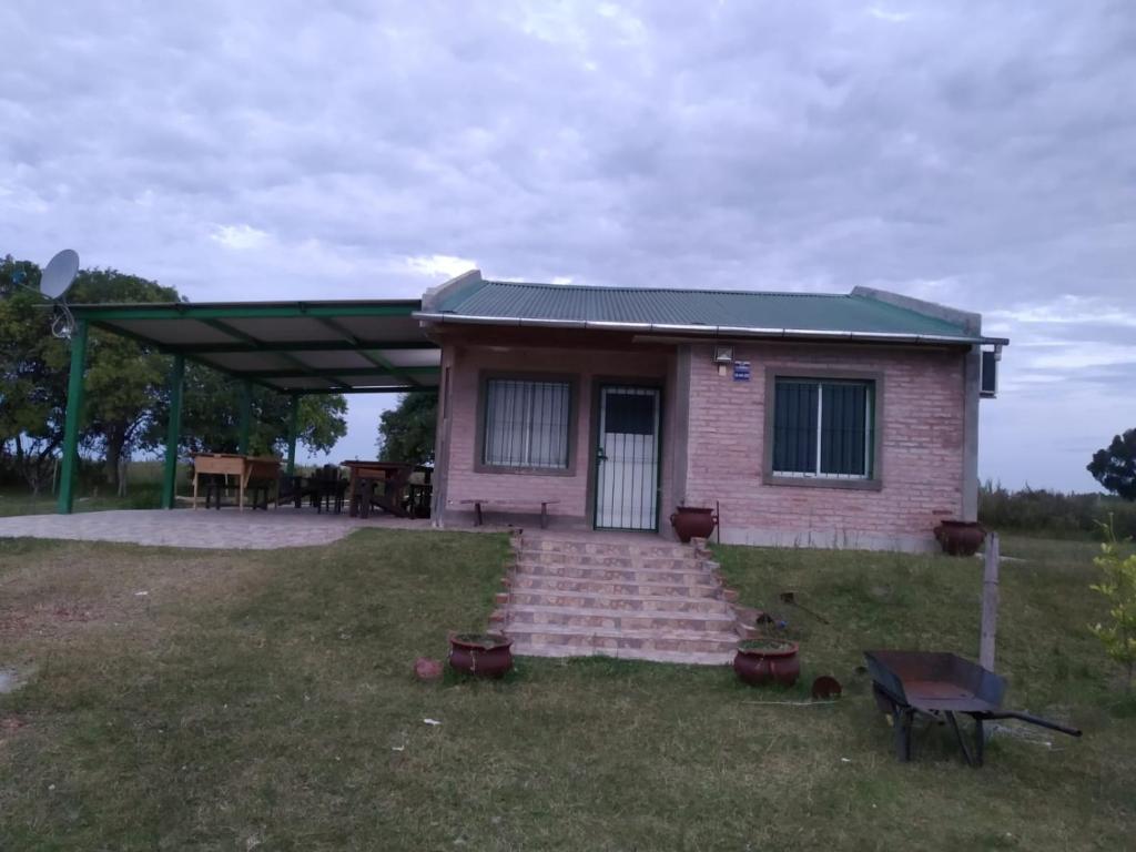 una pequeña casa de ladrillo rosa con techo verde en La Solita, en Mercedes