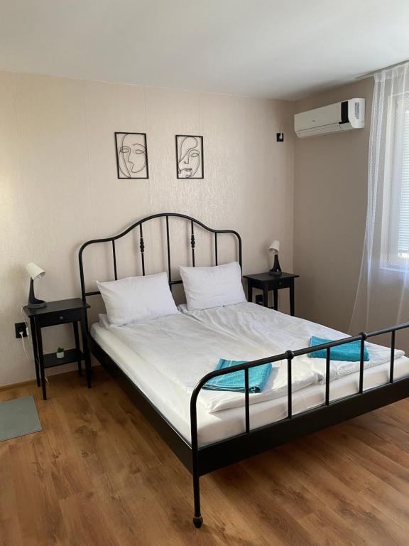 a bedroom with a bed with white sheets and two tables at Къща за гости Германови in Obzor