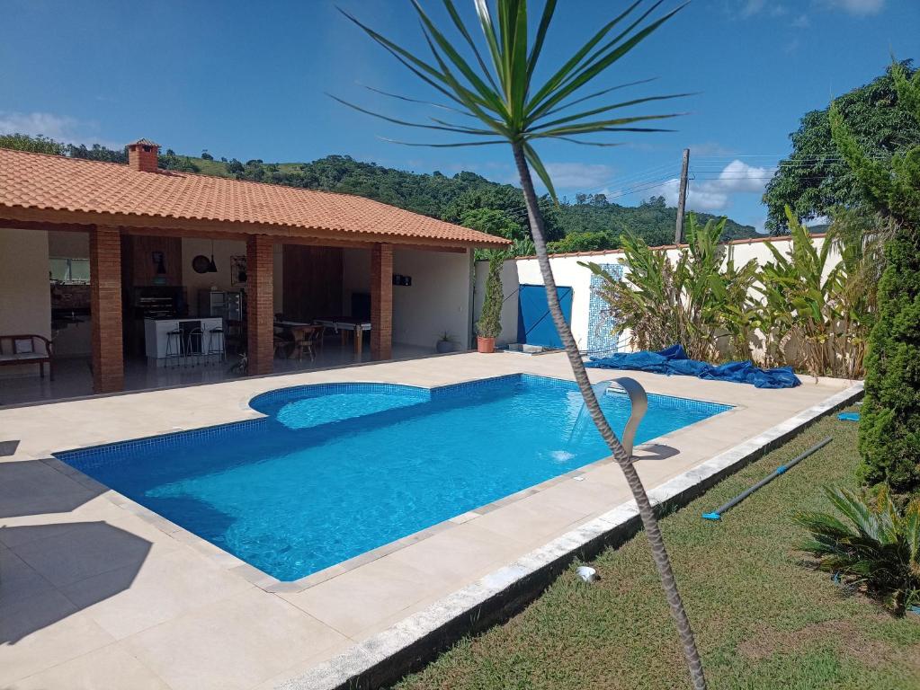 uma piscina com uma palmeira em frente a uma casa em CASA DE CAMPO A TOCA em Guararema