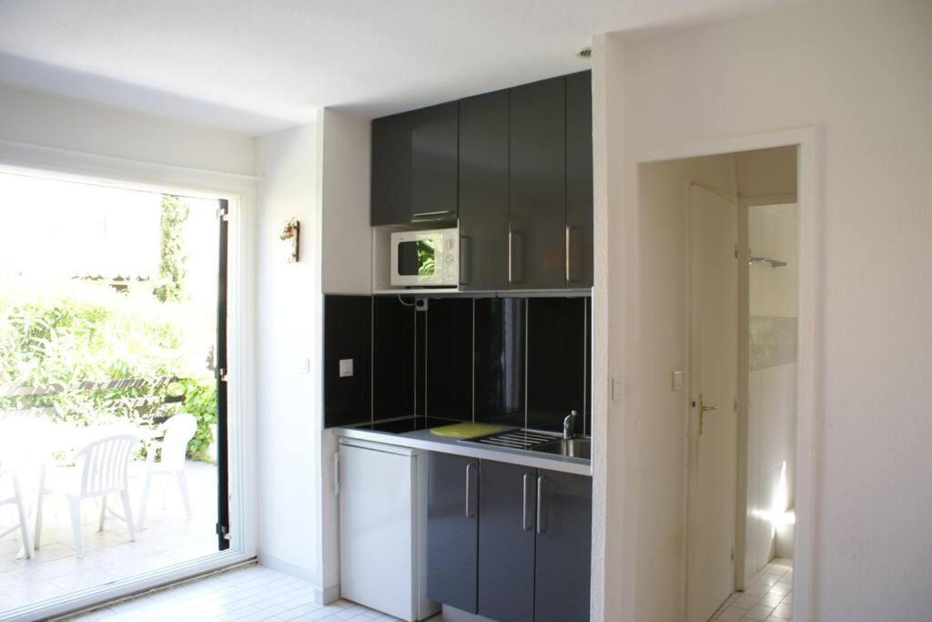 une cuisine avec des armoires noires et un four micro-ondes dans l'établissement Villa 21, port Venus village au village naturiste, au Cap d'Agde