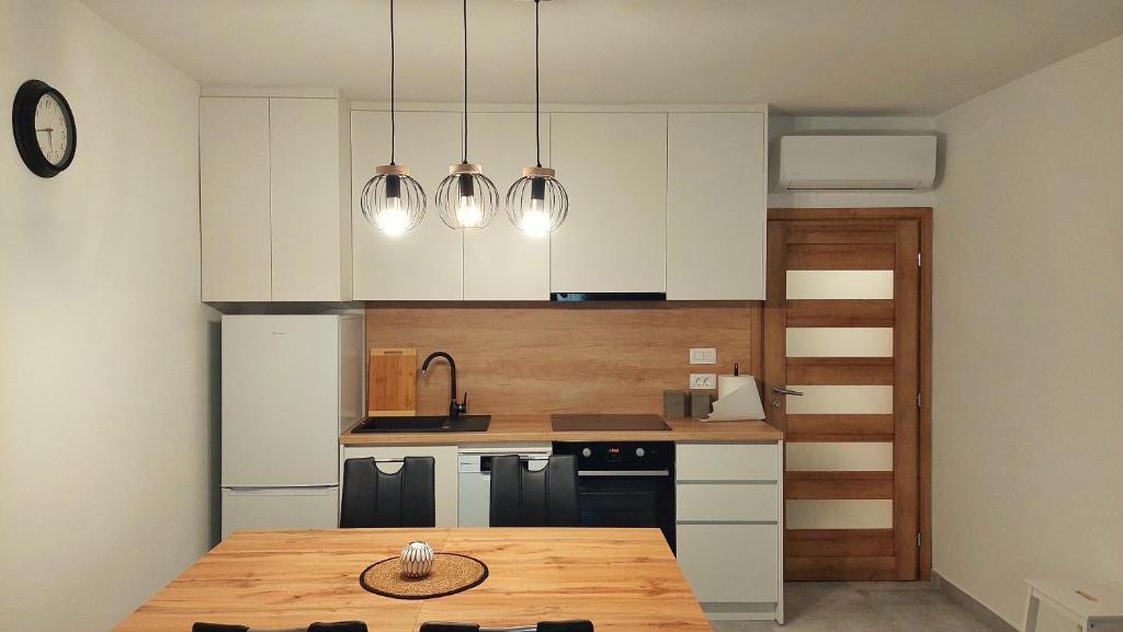 a kitchen with white cabinets and a wooden table at APARTMAN Zengg in Senj