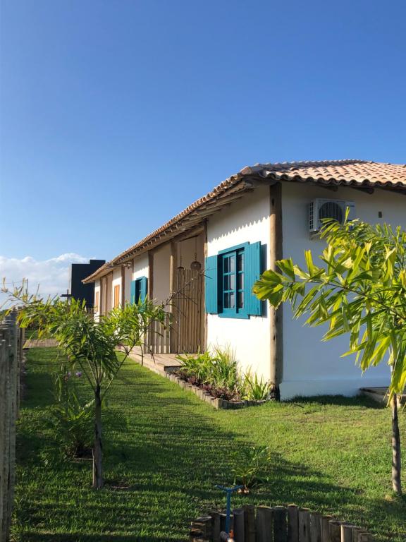 a house with blue shutters and a yard at Vila Aratu Corumbau in Corumbau