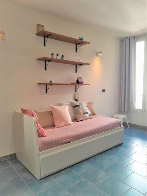 - une chambre dotée d'un lit avec des draps et des étagères roses dans l'établissement Studio Musiciens - CARRE D'OR !, à Nice