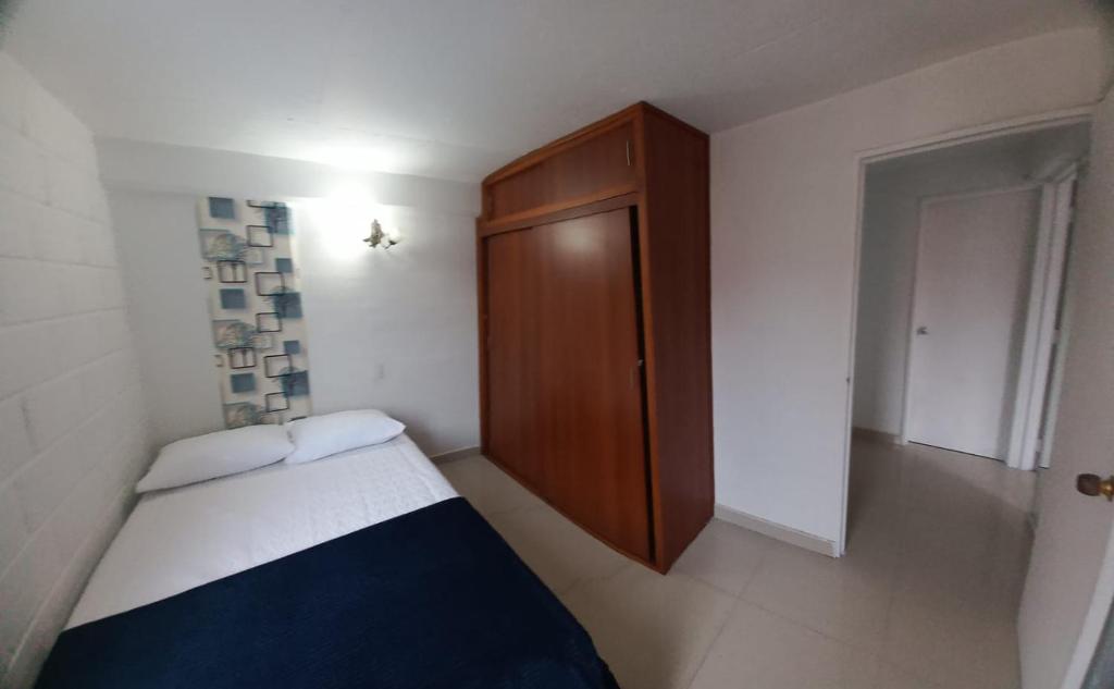 a small bedroom with a bed and a wooden cabinet at La posada de Zophiel in Itagüí