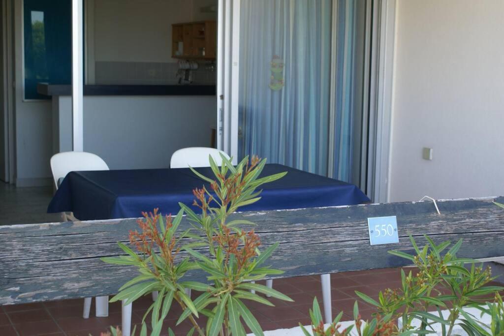 un banc en bois avec une table bleue et quelques plantes dans l'établissement Appartement 550, Port Nature 5, village naturiste, au Cap d'Agde