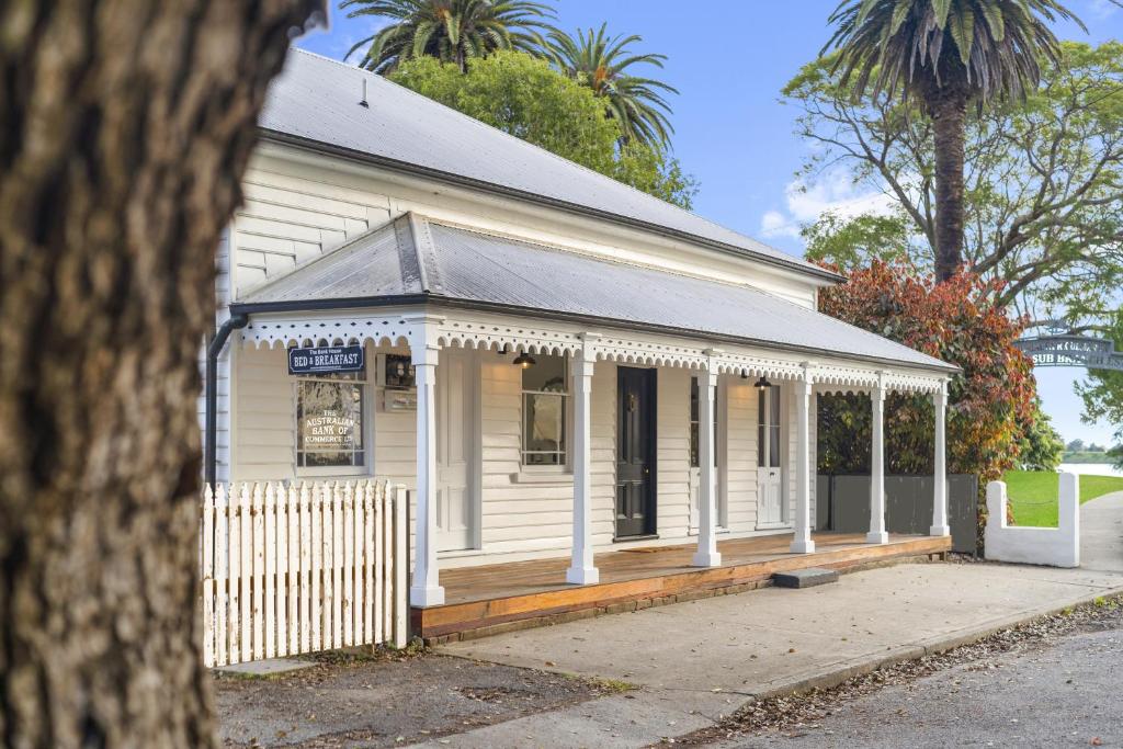 a small white building with a porch and a fence at The Bank House Ulmarra in Ulmarra