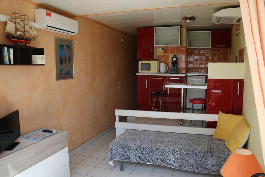 Cette petite chambre dispose d'une cuisine avec des placards rouges. dans l'établissement Studio 729, Port Nature 7 au village naturiste, au Cap d'Agde
