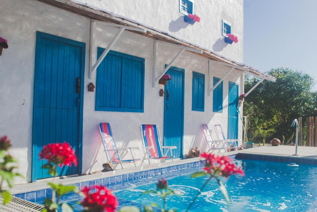 a house with blue doors and chairs next to a swimming pool at Recanto da Sossô in Corumbau