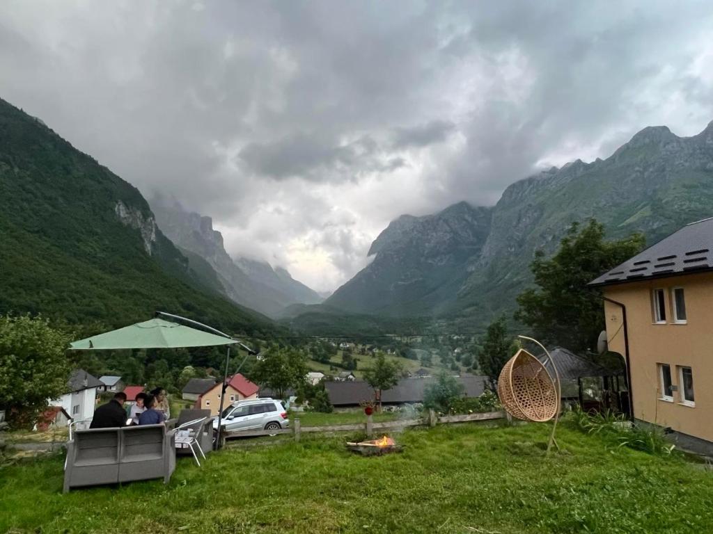 a group of people sitting at a table with a view of mountains at Dedushi Guesthouse &Wood cabins-Camping place in Gusinje
