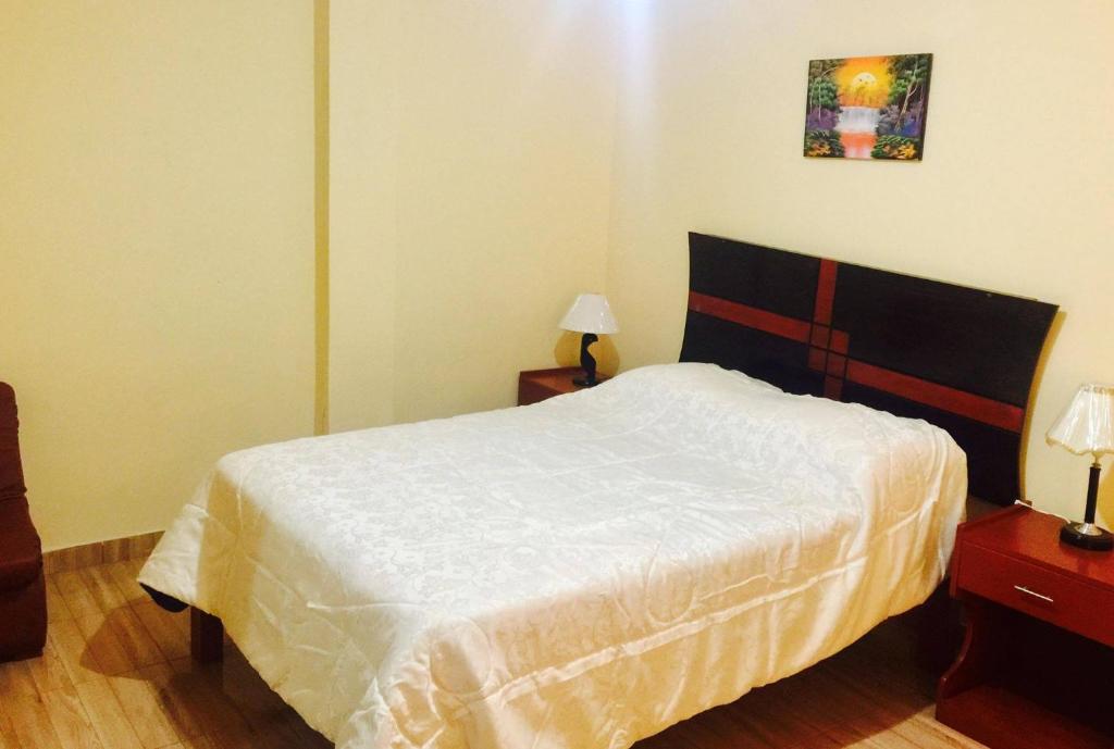 een slaapkamer met een bed en 2 tafels met lampen bij HOTEL CASTILLO MAGICO (EX CHAVIN SEÑORIAL? in Barranca