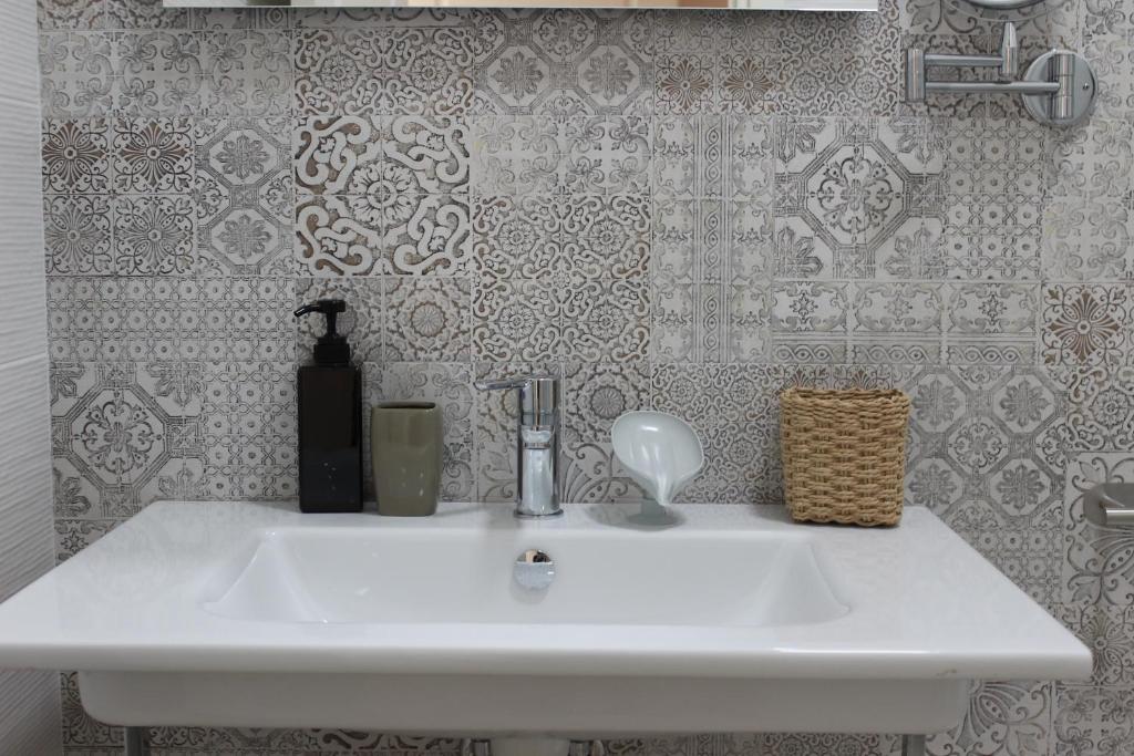 Baño con lavabo blanco y papel pintado en B&B Casa Benvenuto, en Diamante