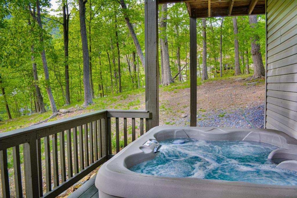 a jacuzzi tub on the porch of a house at In The Woods - 5 BR Chalet with Game Room, Fire Table and Hot Tub in McGaheysville