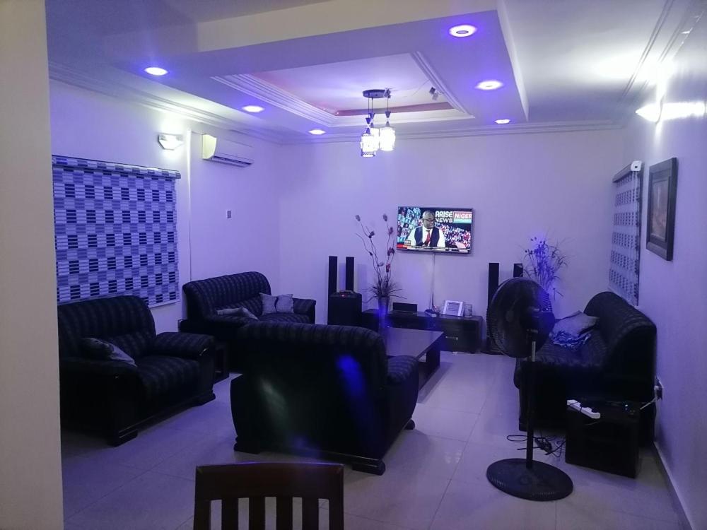 a living room with black couches and a tv at Luxury Homes in Port Harcourt