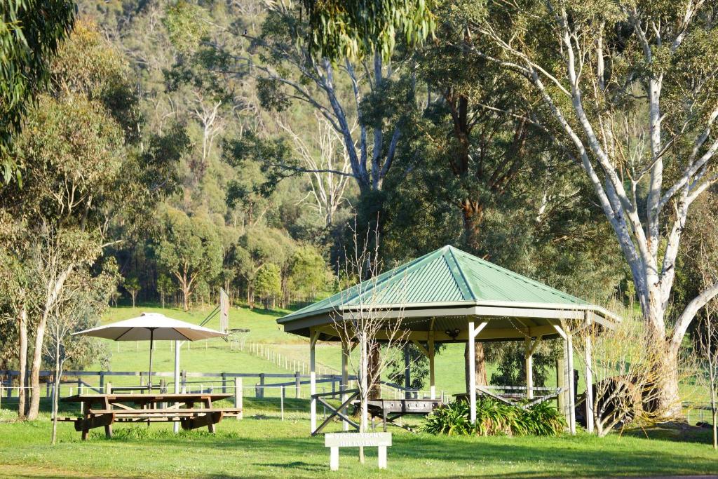 a pavilion with two picnic tables and an umbrella at Halls on Falls Homestead in Strath Creek
