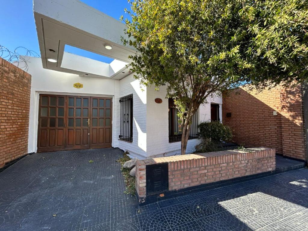 a house with a wooden door and a tree at Casa en SAN LUIS in San Luis