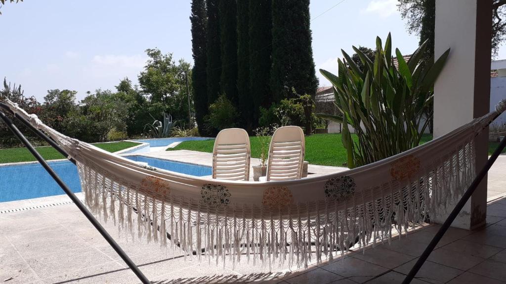 two chairs in a hammock next to a pool at Quarto Amélia in Fogueira