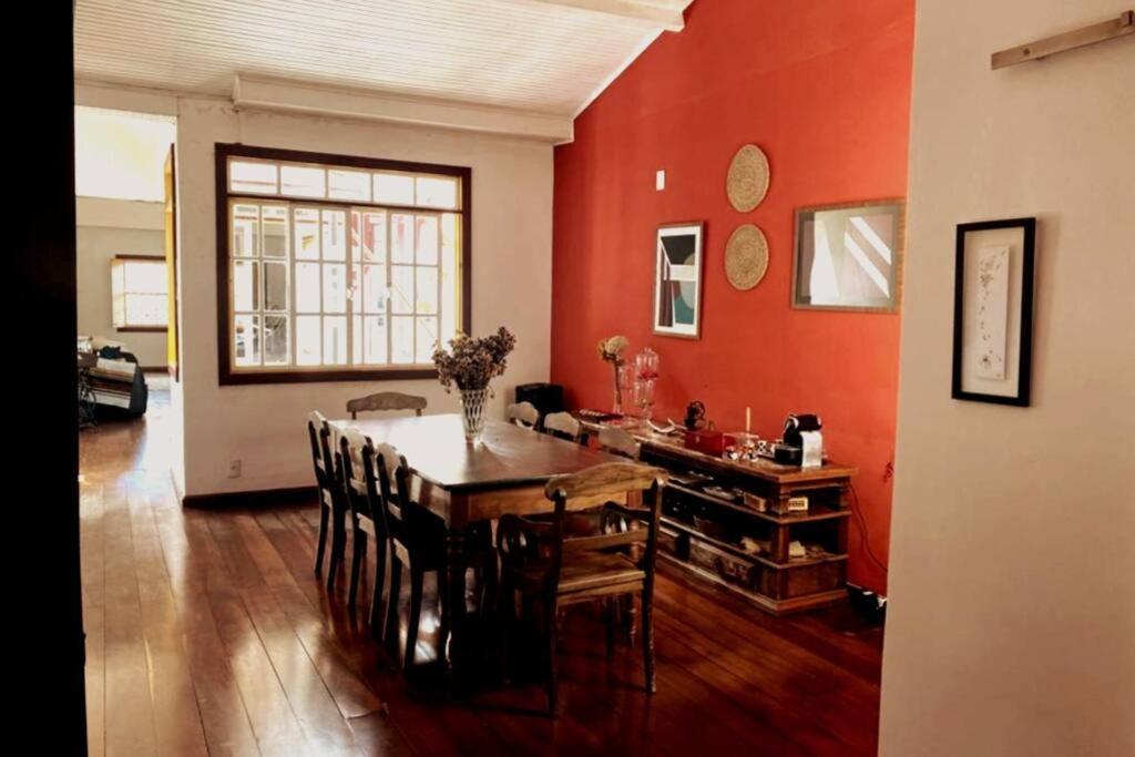 uma sala de jantar com uma mesa e uma parede vermelha em Solar Antônio Dias em Ouro Preto