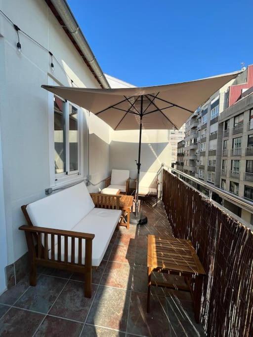 einen Balkon mit zwei Bänken und einem Sonnenschirm in der Unterkunft Atico Vintage con Terraza in Vigo