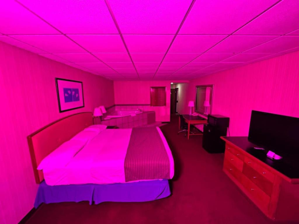 a pink room with a bed and a tv at Travel Inn & Suites in Emporia