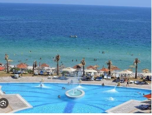 a large blue swimming pool next to the ocean at Appartement S2 Aqua Resort Chott Mariem Sousse in Hammam Sousse