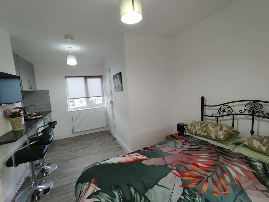 a bedroom with a large bed and a kitchen at Stylish studio flat with Parking in Enfield