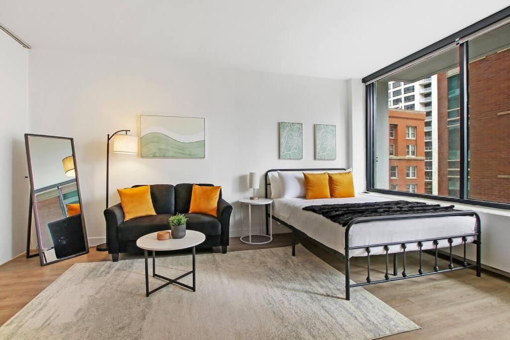 a bedroom with a bed and a couch and a table at Serene & Completely Furnished Studio Apartment- Chestnut 14F in Chicago