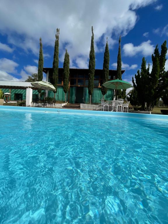 uma piscina em frente a uma casa com árvores em Village Recanto Splendory em Prudente de Morais
